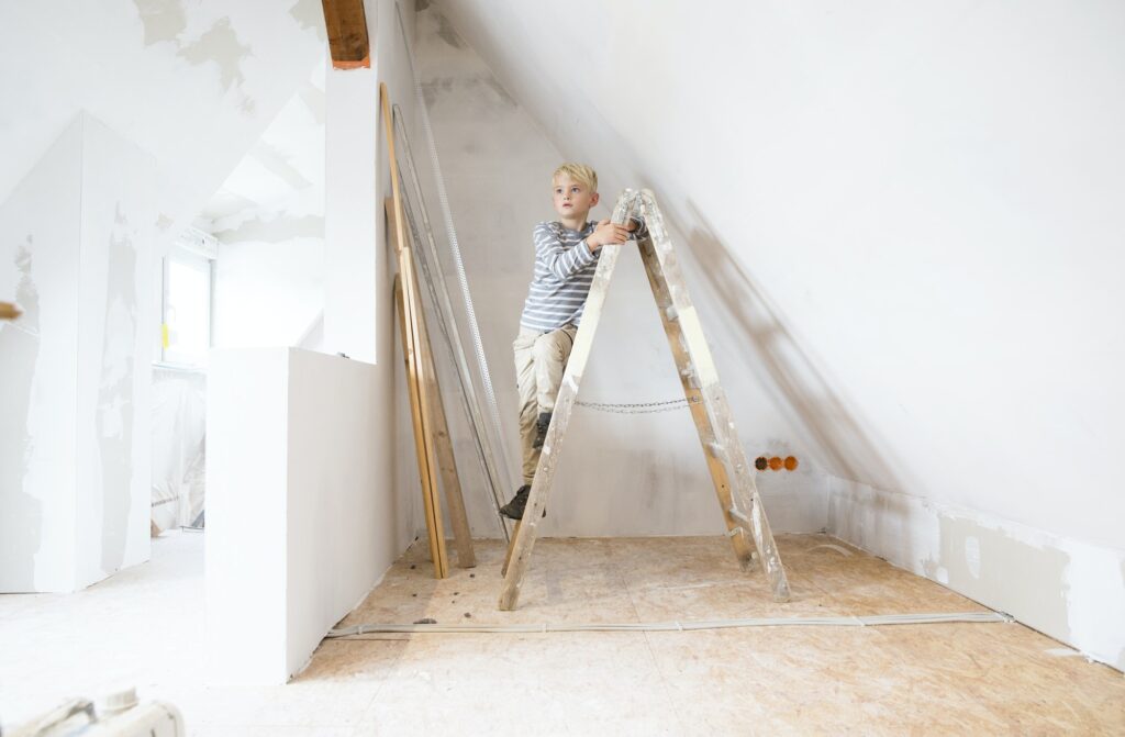Boy standing on ladder in attic to be renovated