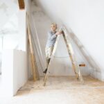 Boy standing on ladder in attic to be renovated