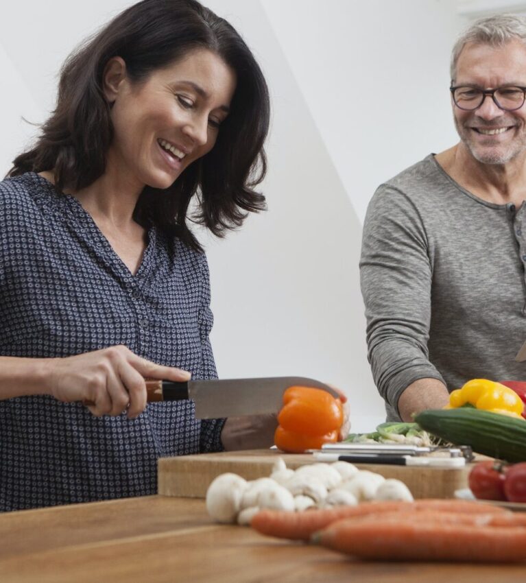 Mature couple with digital tablet cooking in kitchen