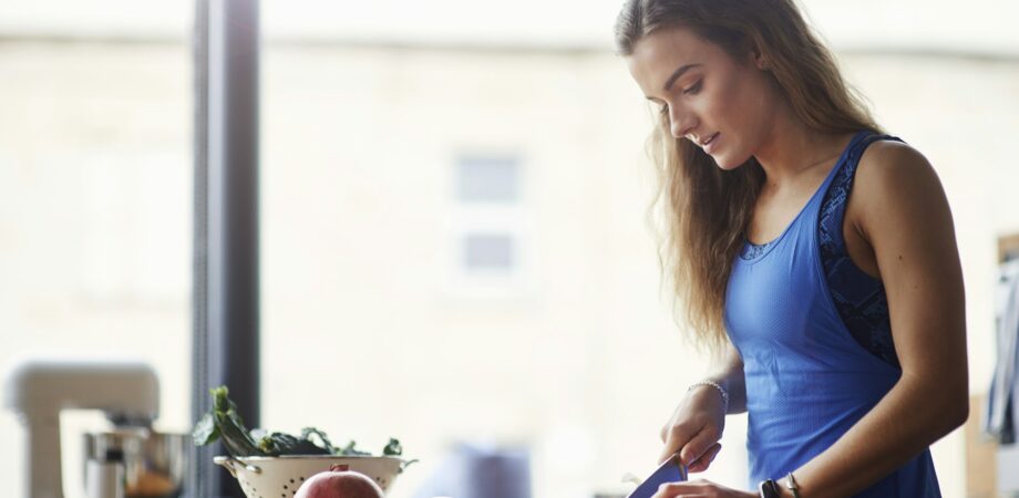 Young woman at kitchen table slicing vegetables