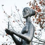 Bronze sculpture of mournful woman holding burning candle