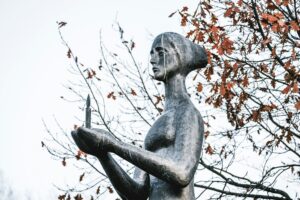 Bronze sculpture of mournful woman holding burning candle