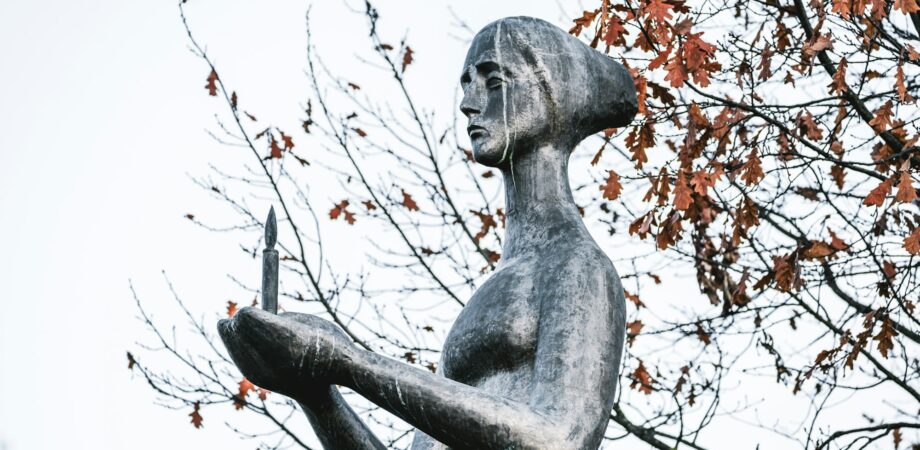 Bronze sculpture of mournful woman holding burning candle